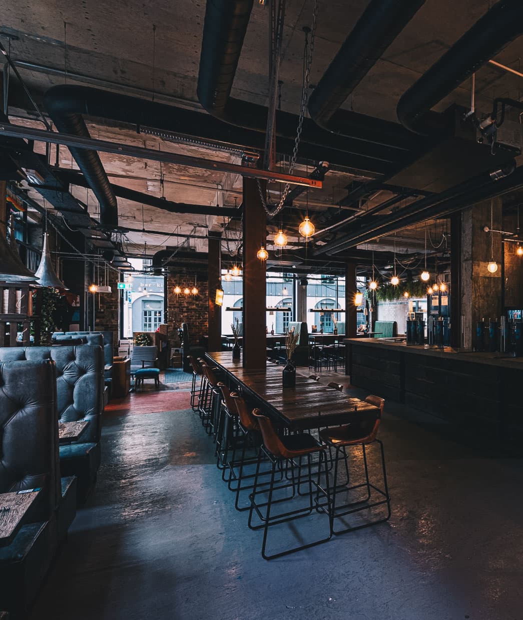 Bar area with pendant lights, booth seating and exposed industrial ceiling at The Bellman